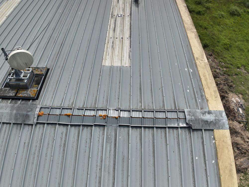 Close-up of the steel-clad hangar roof, showing weathering around the central flashing and around the securing screws
