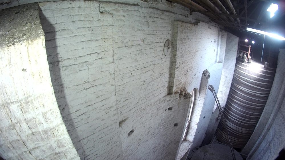 Drone's-eye view looking down at giant wooden storage vats suspended above the cast iron lattice work inside the old vat house