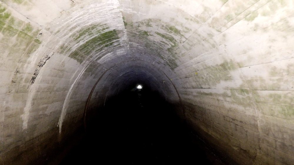 The ELIOS 3 confined space drone operating inside a culvert with its LED lighting illuminating the walls