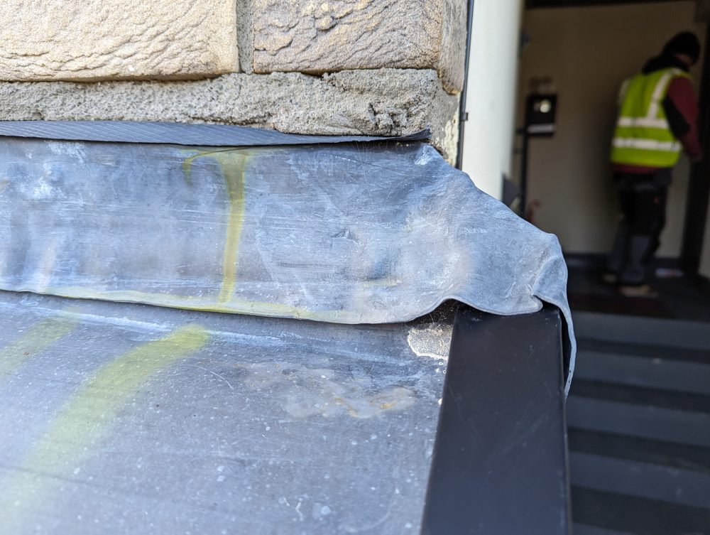 A close-up view of defective flashing on a roof edge showing poor workmanship