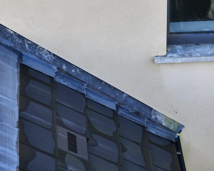 A drone's-eye view of a housing estate roof showing defective flashing areas