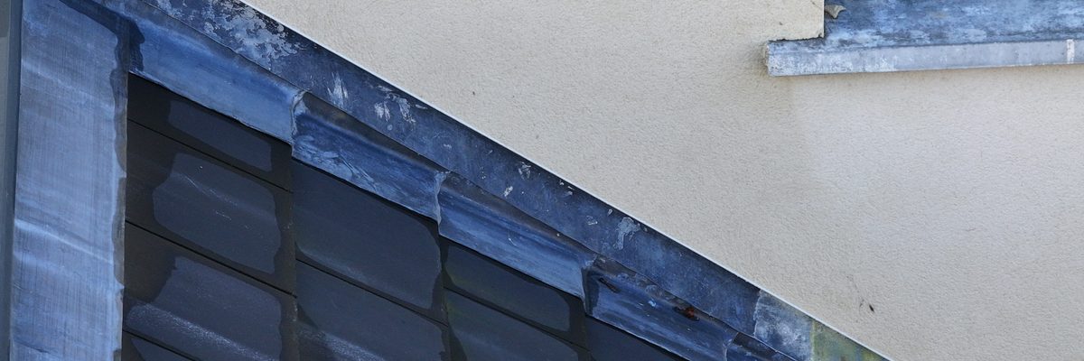 A drone's-eye view of a housing estate roof showing defective flashing areas