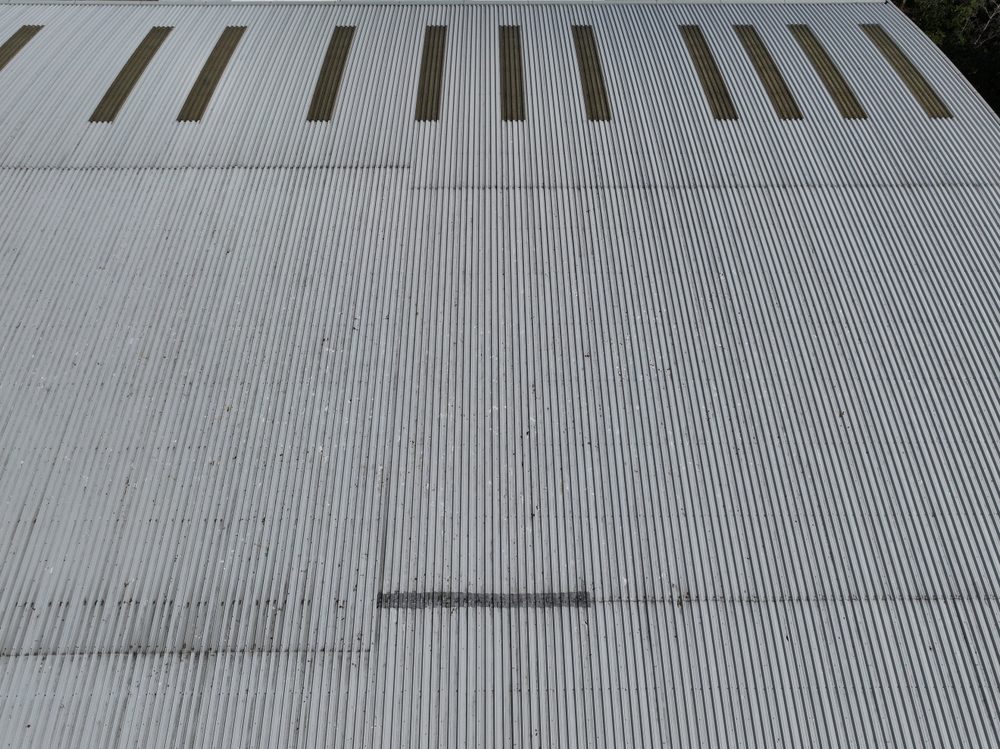 Top-down drone view of the warehouse roof showing rows of aged translucent roof panels set into the sheeting