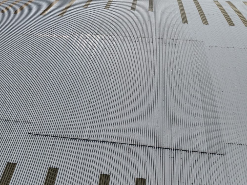 Wide drone view across the warehouse roof, showing the translucent roof panels and rows of fixings running across the sheeting