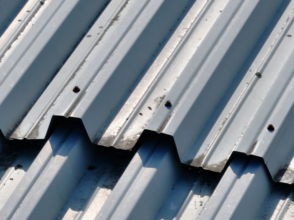 Close-up drone image of an over-sheet lap on the warehouse roof, showing fixings along the joint and rust staining on the sheeting