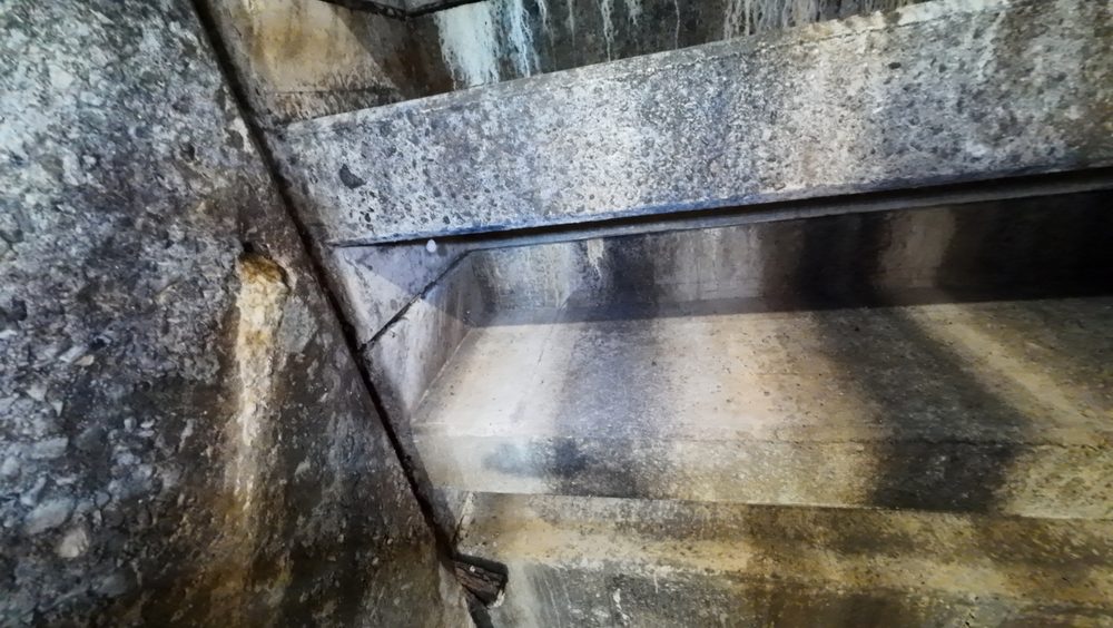 Close-up of concrete spalling and cracking on a spillway interior wall