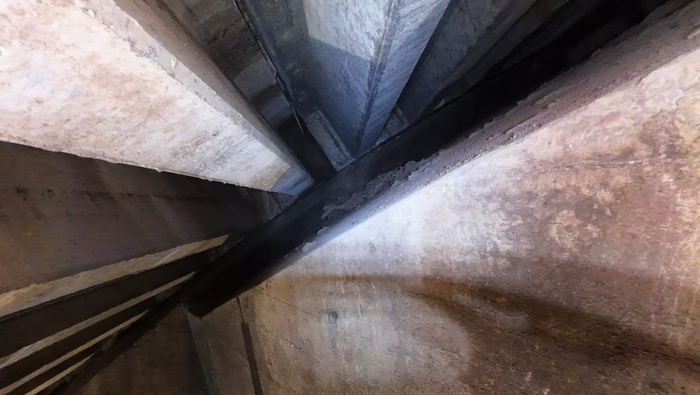 Calcite buildup and weeping on a concrete surface inside the spillway