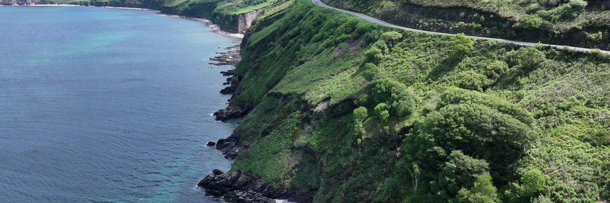Coastal cliff view showing the road hugging the cliffside above the sea at Mountain Stages, Kerry