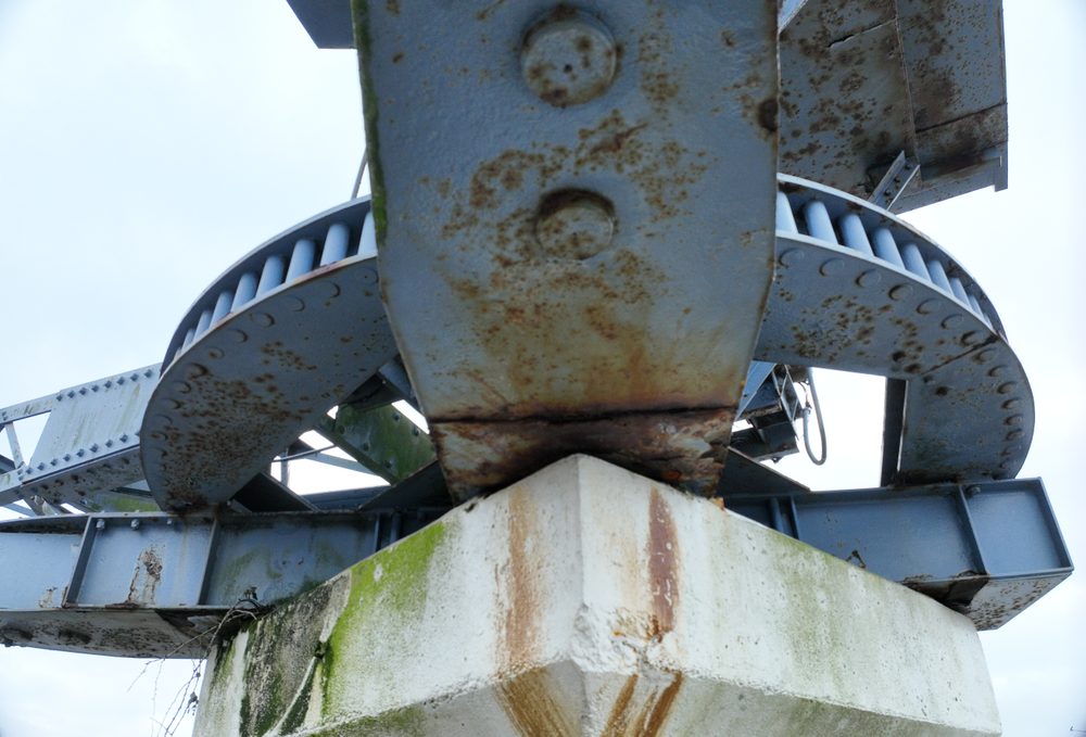Low-angle close-up of the crane's main rotational gear mechanism and concrete base