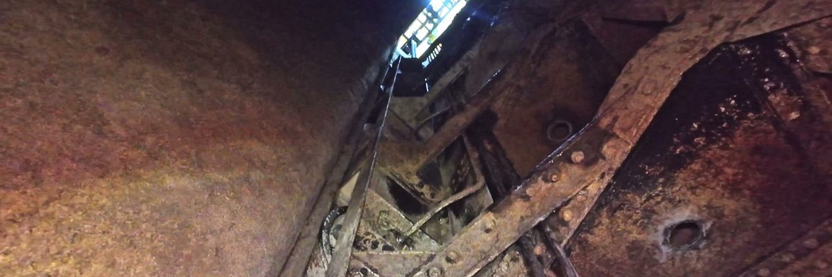 Inside the fully drained penstock at Ardnacrusha Power Station, looking up along the riveted steel walls towards the daylight opening at the top