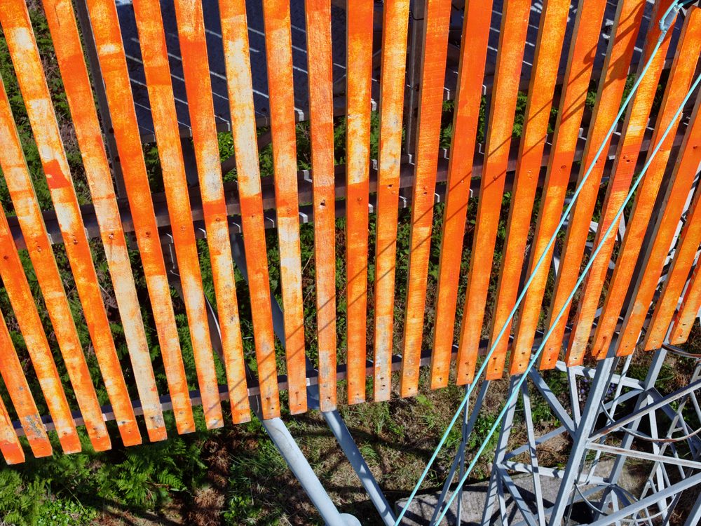 A close-up of the slatted orange board, showing the vertical orange panels fixed to the steel frame