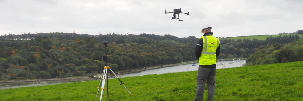 A land surveyor flying a drone during a drone survey mission