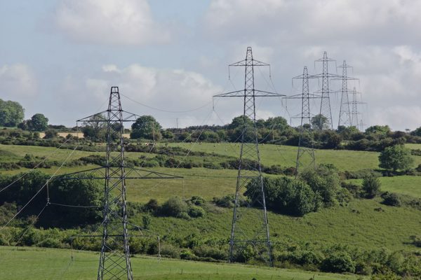 A row of electrical pylons being inspected by a drone