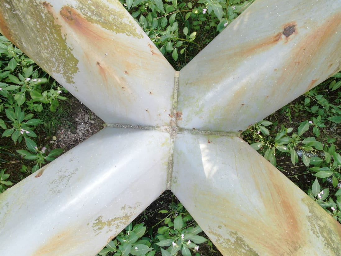 A view looking down of the tetrapod pier of this bridge showing some corroded areas where the surface finish has failed.