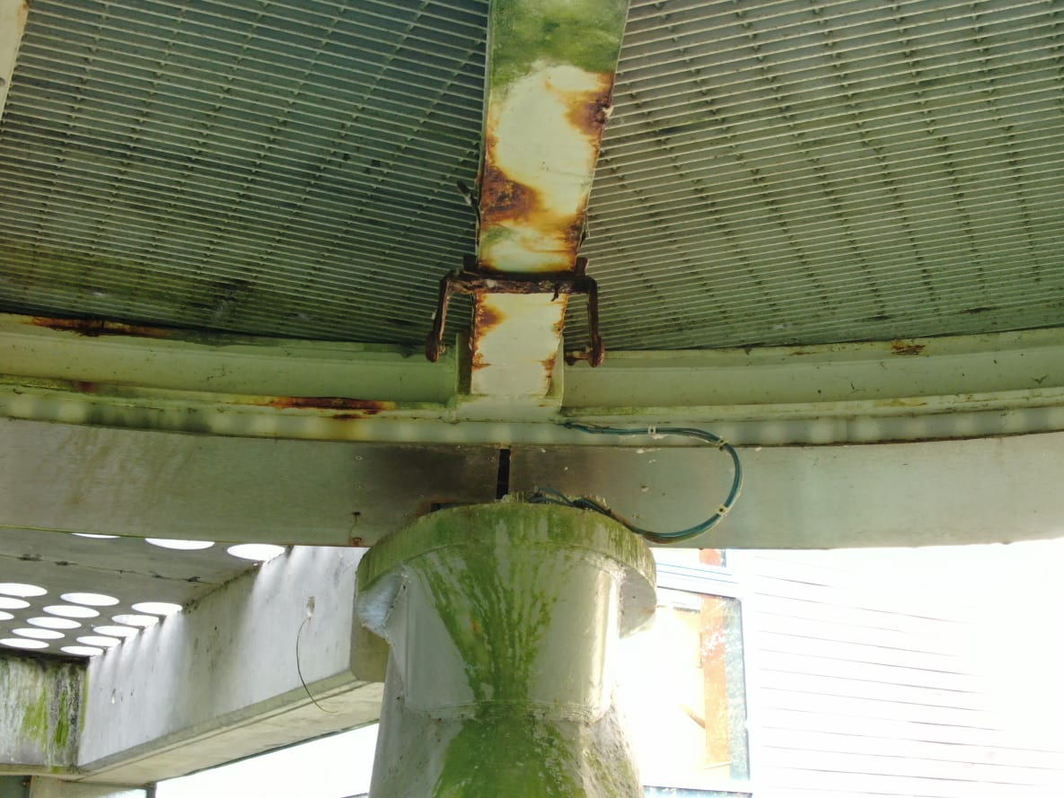 A view looking up at of the arms of the tetrapod pier showing some corroded areas of the soffit and also a  missing light fixture.