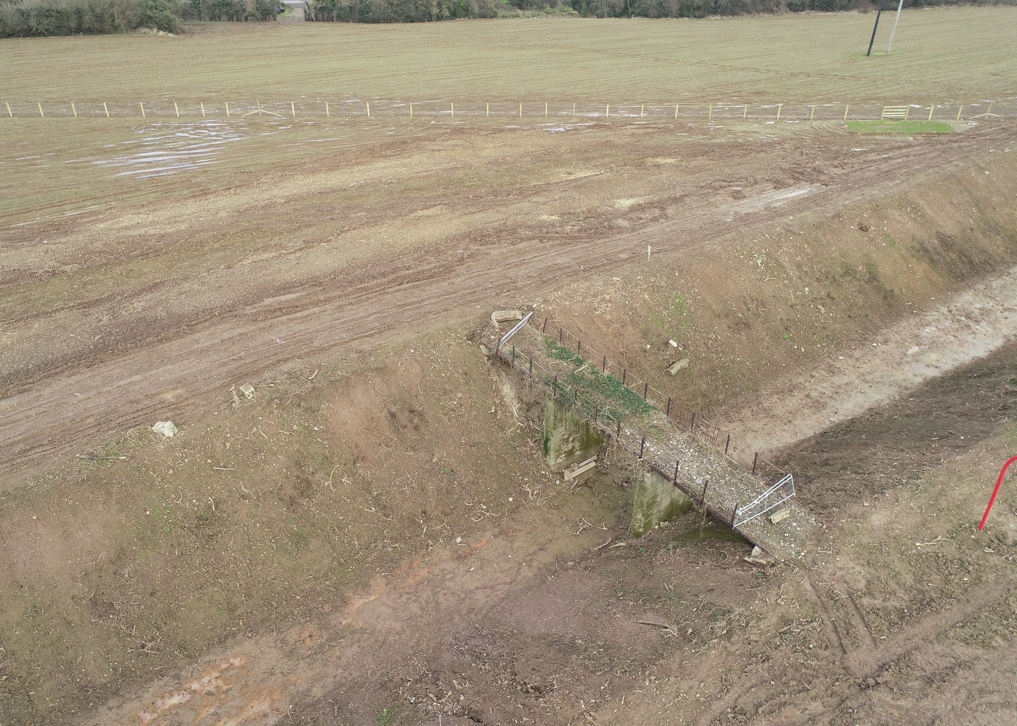 A muddy field fully of soil with a bridge