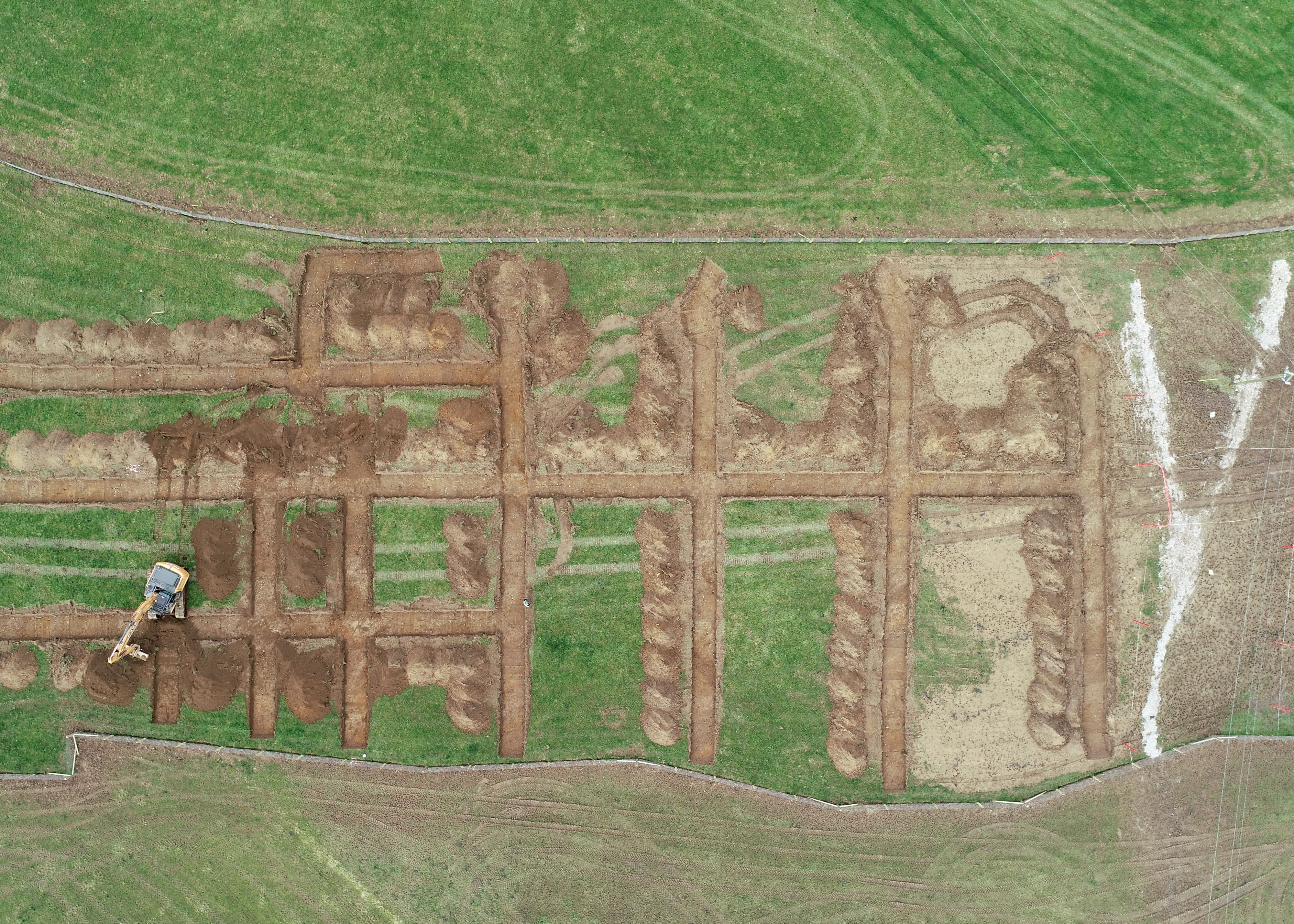 A series of trenches in a field being inspected