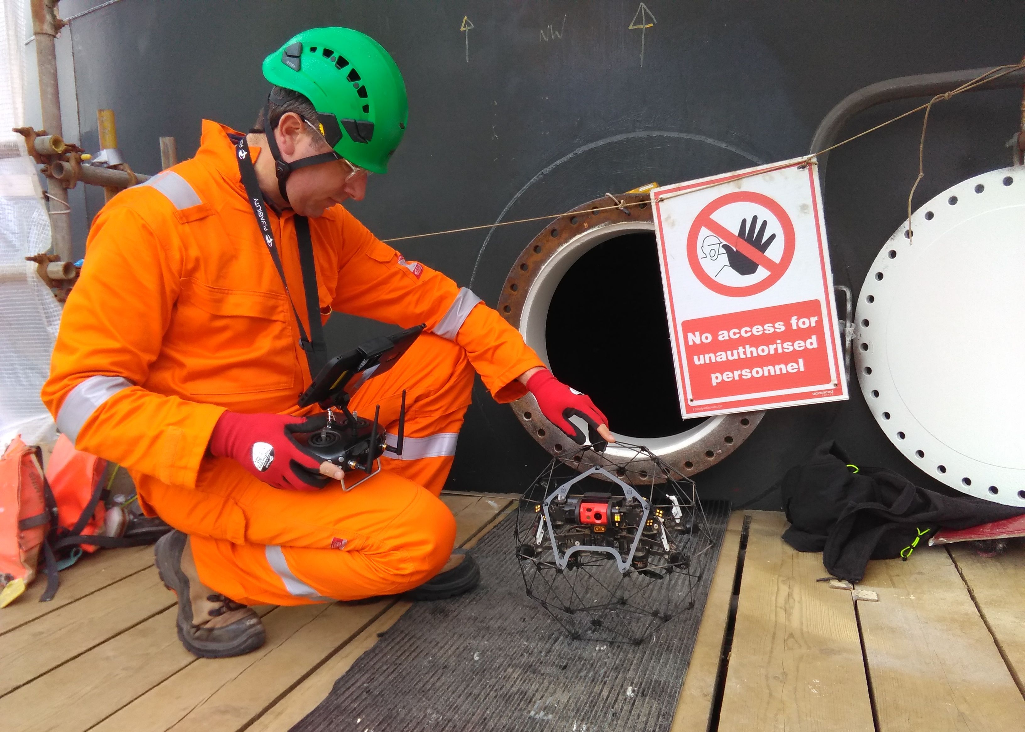 A man with a confined space drone in front of some oil and gas infrastructure