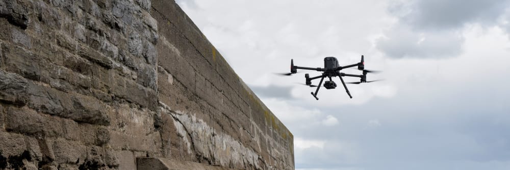 A DJI inspection drone inspecting the wall of a coastal pier